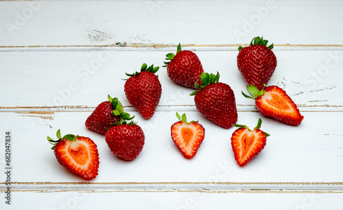Fresh red strawberries, scattered organic strawberries on a white wooden background, close-up.