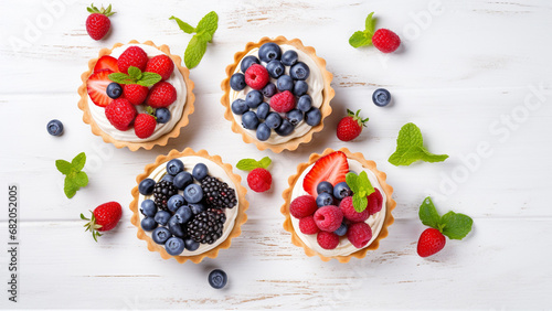 Tartlets with cream, blueberries, raspberries and strawberries on white table