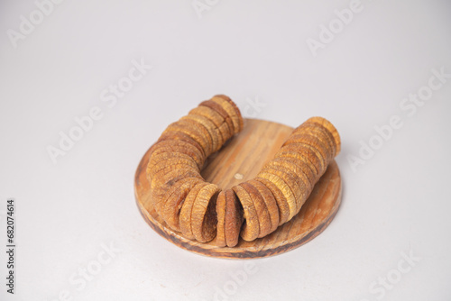 Figs or dried figs on white bowl with white background, Figs or dried figs arranged in round shaped on the white background in a wooden bowl. The fig is the edible fruit of Ficus Carica
