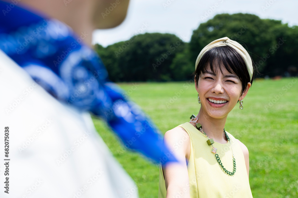 Beautiful Asian woman strolling hand in hand with her lover on the grass of a lush park. Beautiful Asian woman strolling hand in hand with her lover on the grass of a lush park.