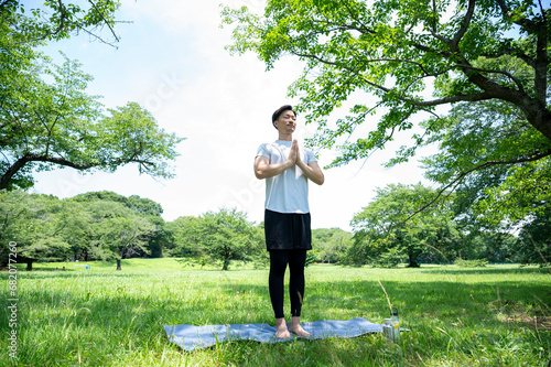 Obraz na plátně Asian man in sportswear practising yoga in a beautiful grassy park
