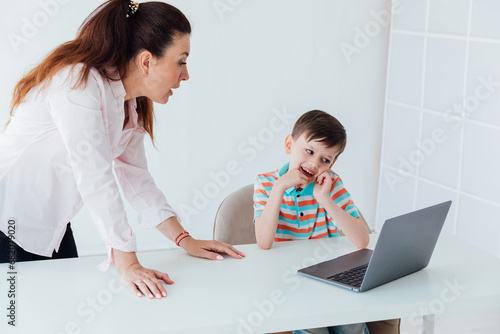 Female teacher teaching boy to use computer photo