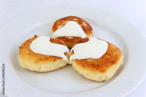 Delicious, ruddy cheesecakes covered with sour cream on a white plate.