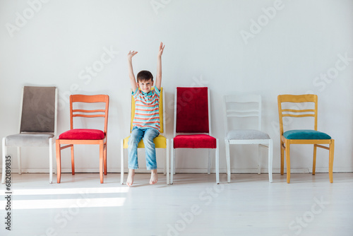 Cheerful little boy and many different colored chairs