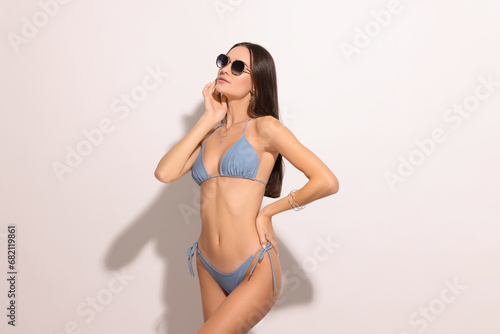 Young woman in stylish bikini and sunglasses on white background © New Africa