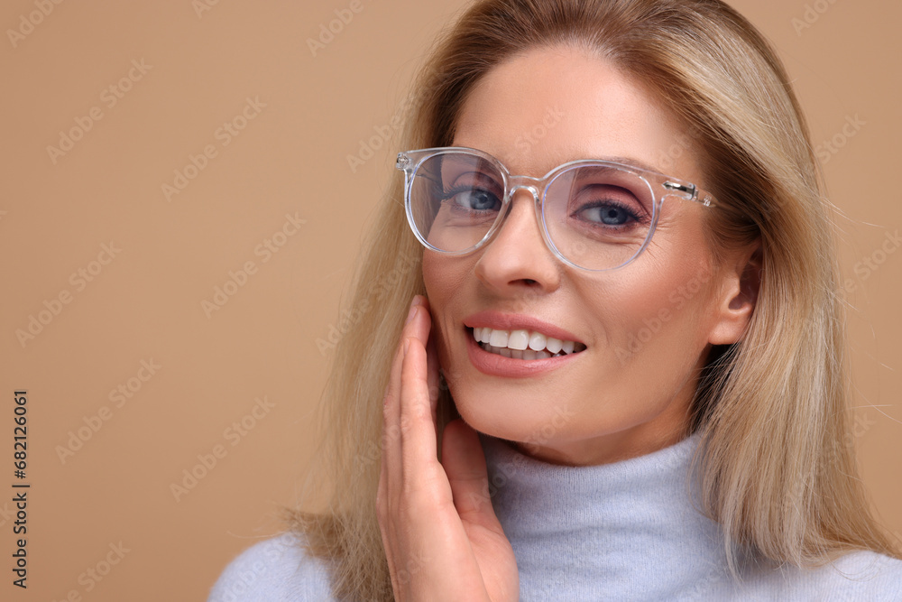 Portrait of smiling middle aged woman in glasses on beige background. Space for text Portrait of smiling middle aged woman in glasses on beige background. Space for text