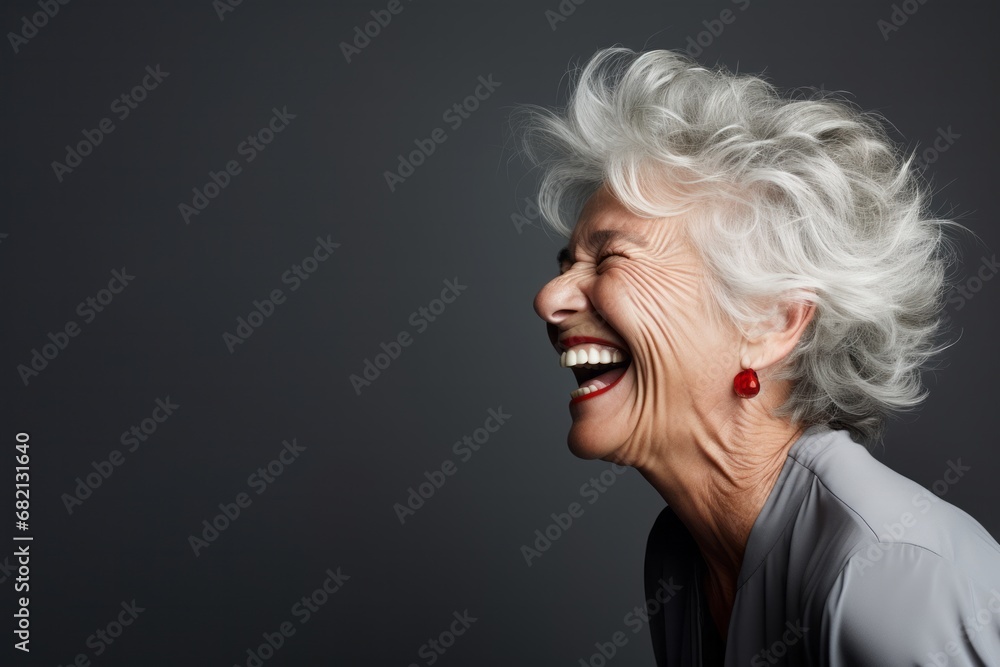 Portrait of senior woman smiling isolated over grey background.