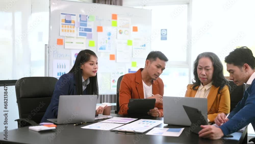 Happy businesspeople while collaborating on a new project in an office. Group of diverse businesspeople using a laptop and tablet . Happy businesspeople while collaborating on a new project in an office. Group of diverse businesspeople using a laptop and tablet .