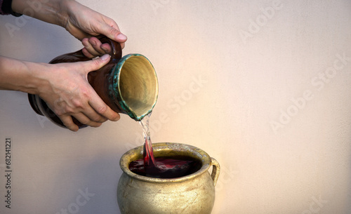 A hand holds a clay jar and pours water photo