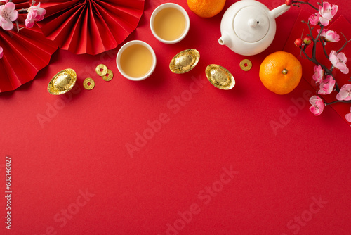 Chinese New Year Feast Delight. Top-view shot showcasing red envelopes, traditional ornaments, tea set for family gatherings, citrus fruits, vibrant decor on red background with space for text or ad