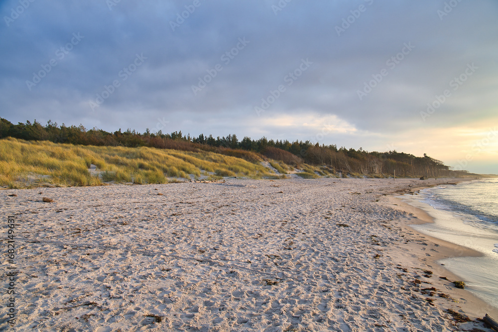 Sunset on the west beach on the Baltic Sea. Waves, beach, cloudy sky and sunshine Sunset on the west beach on the Baltic Sea. Waves, beach, cloudy sky and sunshine
