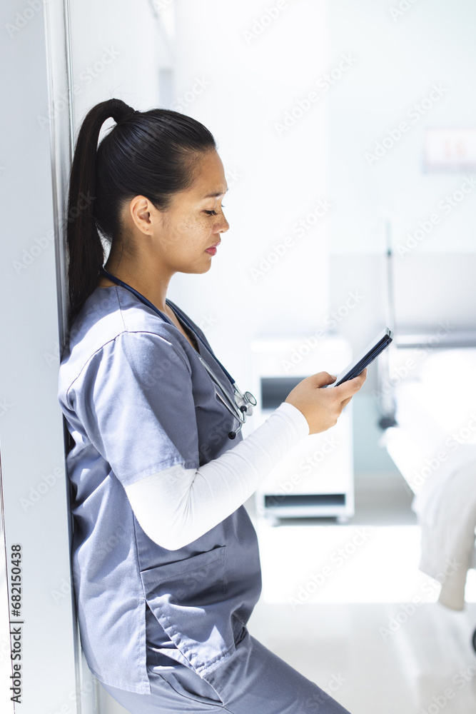 Biracial female doctor wearing scrubs using smartphon in hospital Biracial female doctor wearing scrubs using smartphon in hospital
