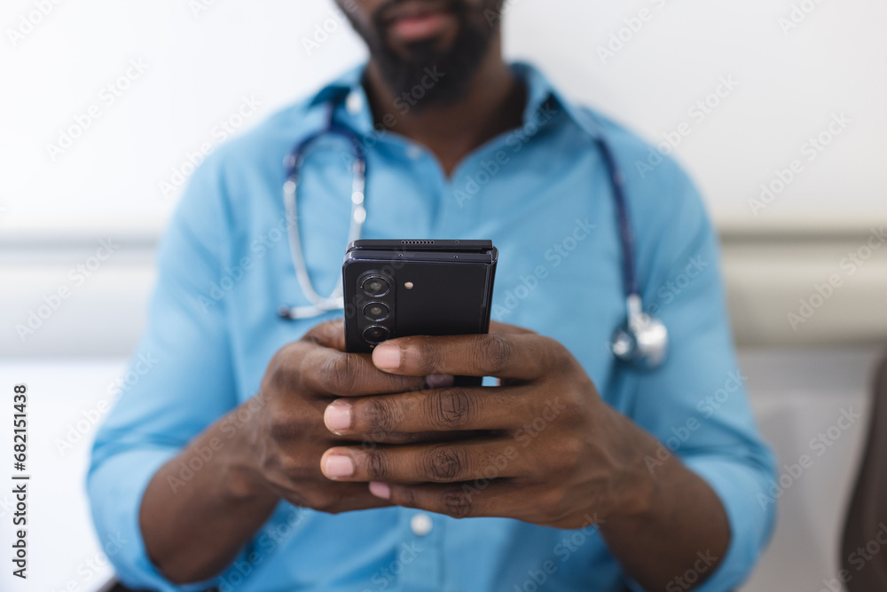 Midsection of african american male doctor using smartphone in waiting room in hospital Midsection of african american male doctor using smartphone in waiting room in hospital