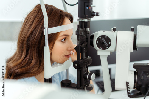 Pretty young woman sitting at an eye tester photo