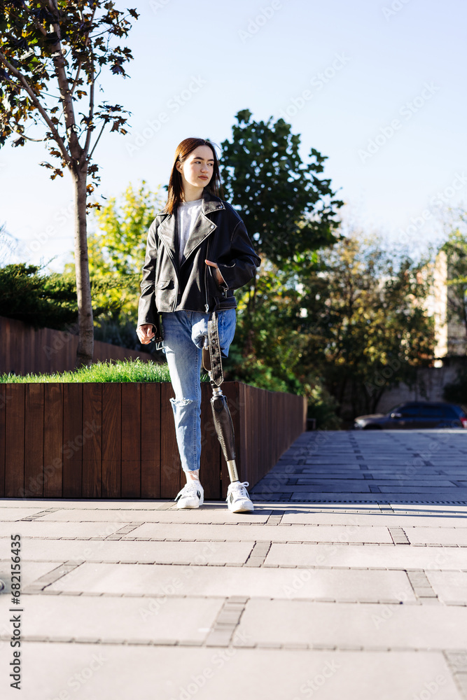 Portrait of young woman with prosthetic leg staying in city. Woman with prosthetic leg. Woman with leg prosthesis equipment
