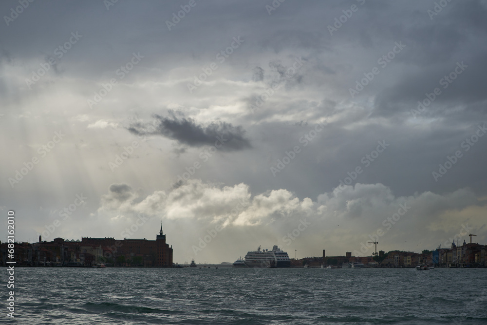 Sun rays and dramatic clouds at the entrance to Venetian lagoon on Guidecca canal. Venice - 4 May, 2019