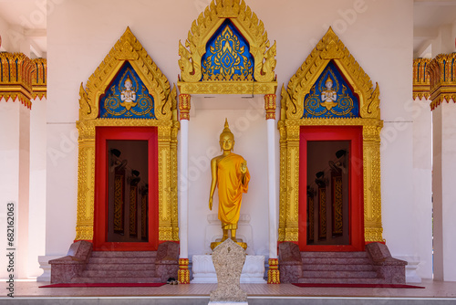 Statue of a Golden Buddha outside the doors of Wat Mongkhon Nimit Buddhist Temple, Phuket Old Town, Thailand