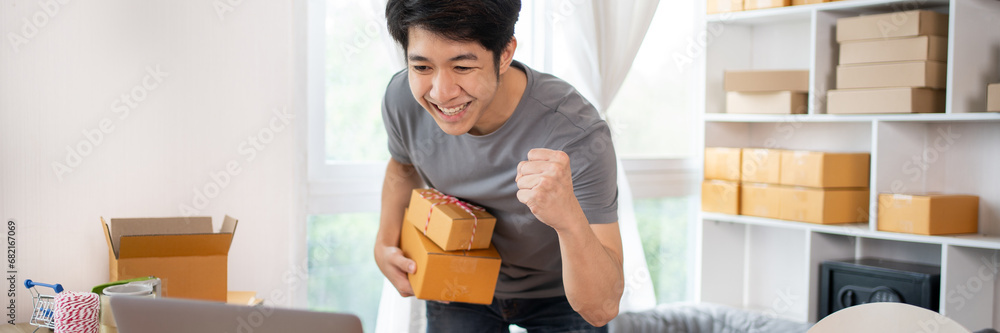 Happy man Celebrating Order from Internet Customer: New Business Style at Home, Online Selling, Young Entrepreneur's Success: Work-from-Home SME Owner Thrives in Online Sales, Packing Box. Happy man Celebrating Order from Internet Customer: New Business Style at Home, Online Selling, Young Entrepreneur's Success: Work-from-Home SME Owner Thrives in Online Sales, Packing Box.