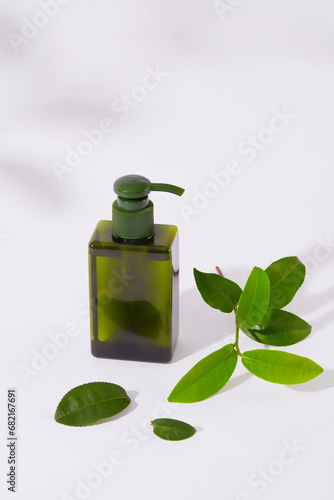 Hand sanitizer bottle with spray head and fresh green tea leaves placed on white background. Green tea has antiseptic and cleansing effects, and has a pleasant aroma, so it is very popular.