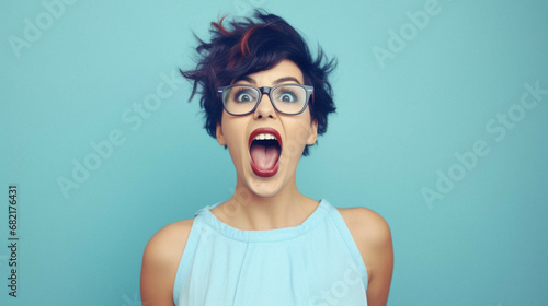 Young beautiful woman with blue hair wearing elegant glasses over blue isolated background afraid and shocked with surprise expression, fear and excited face. face is excited.