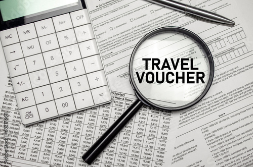 TRAVEL VOUCHER word on magnifying glass with calculator and documents