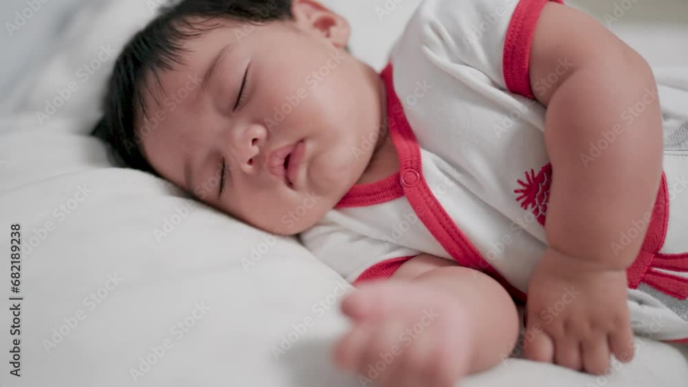 Close-up face of chubby newborn baby lying on stomach, eyes open and smiling with blanket on bed. Close-up face of chubby newborn baby lying on stomach, eyes open and smiling with blanket on bed.