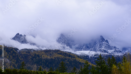montagne enneigée dans la brume, avec colline d'arbres aux nuances de couleurs d'automne, ambiance mystérieuse