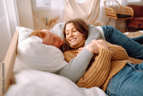 Portrait of a loving couple resting on the bed at home, hugging. A man and a woman enjoy the comfort of home, spending time together. Concept of love, relaxation.