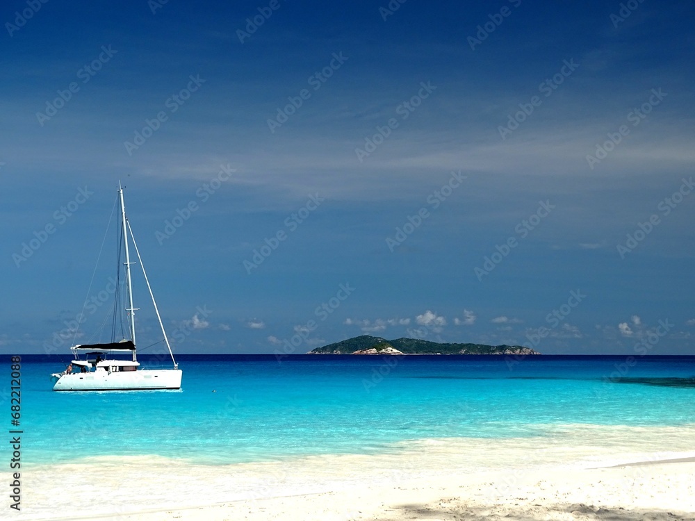 Island and sailboat on a shade of blue ocean