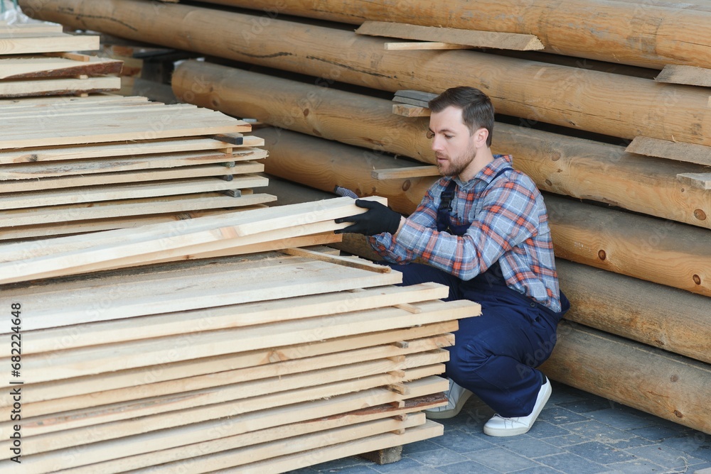 Carpenter in uniform check boards on sawmill