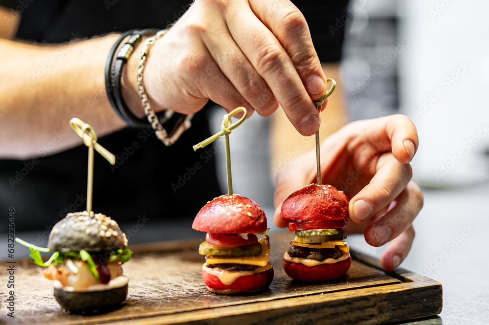 chef hand cooking set mini hamburgers, mini burgers on restaurant kitchen - obrazy, fototapety, plakaty 