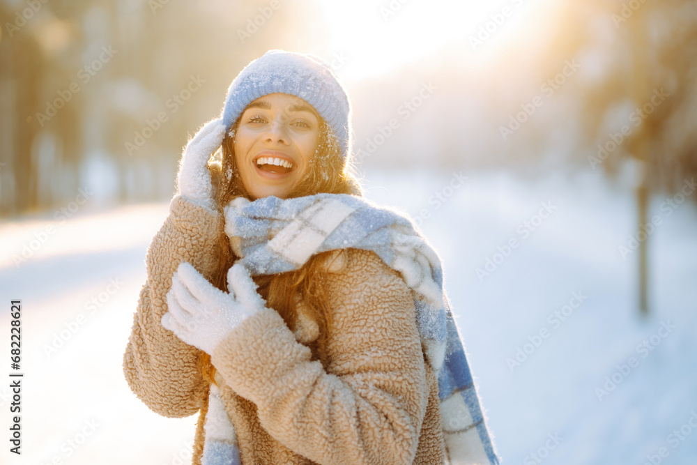 Laughing beautiful woman in the winter forest enjoying an amazing sunset. Great mood on the first snow. The girl is dressed in a fur coat, hat, and scarf. Walking concept. Laughing beautiful woman in the winter forest enjoying an amazing sunset. Great mood on the first snow. The girl is dressed in a fur coat, hat, and scarf. Walking concept.