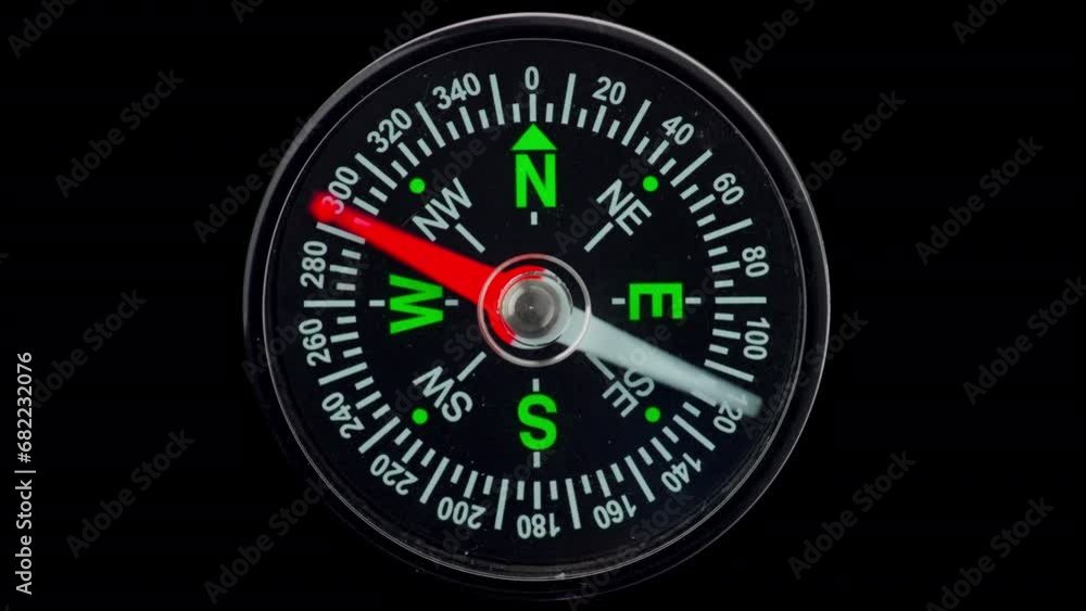 Modern magnetic compass on a black background, with a red arrow defining the direction. Modern magnetic compass on a black background, with a red arrow defining the direction.