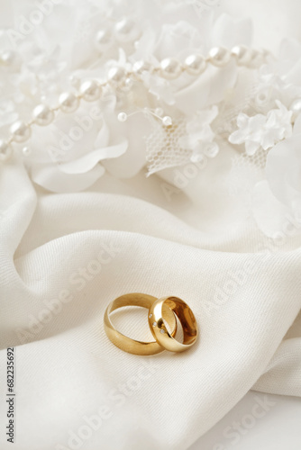 golden wedding rings, pearls and white flowers