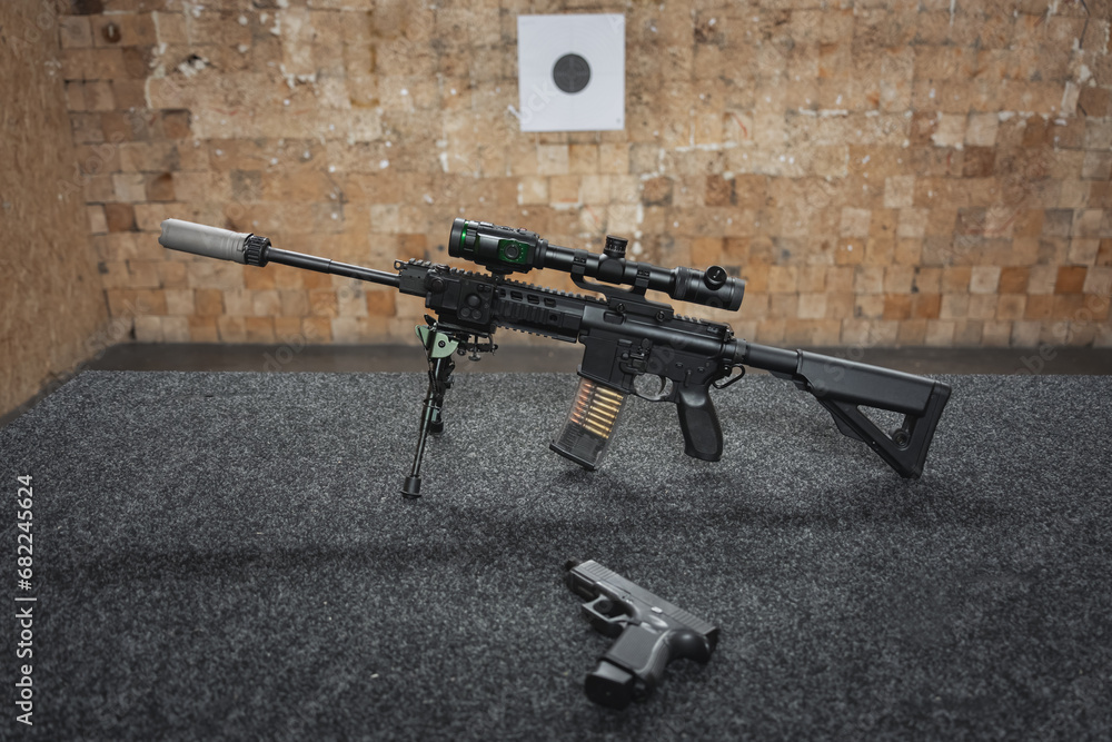 An ar 15 rifle with a digital night vision sight and a pistol on a ...