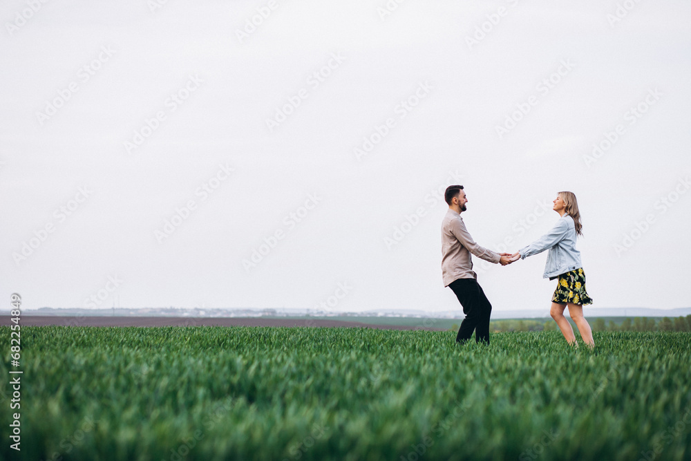 Young couple in the field with green grass