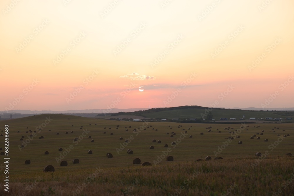 Beautiful view of agricultural field with hay bales at sunset