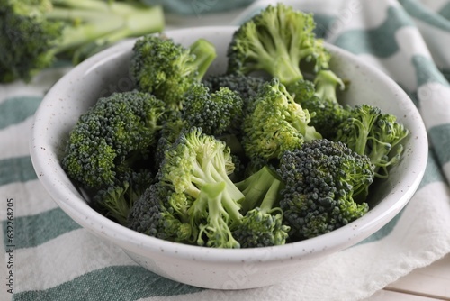 Bowl with fresh raw broccoli on white table, closeup