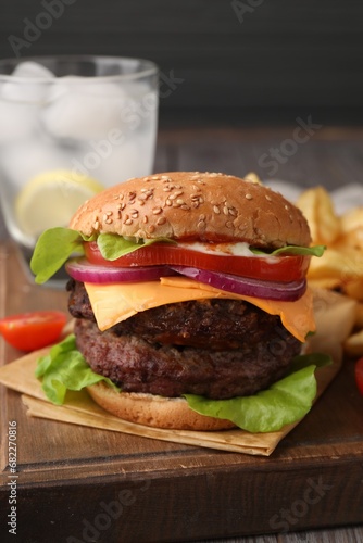 Tasty cheeseburger with patties, onion and tomato on wooden board, closeup