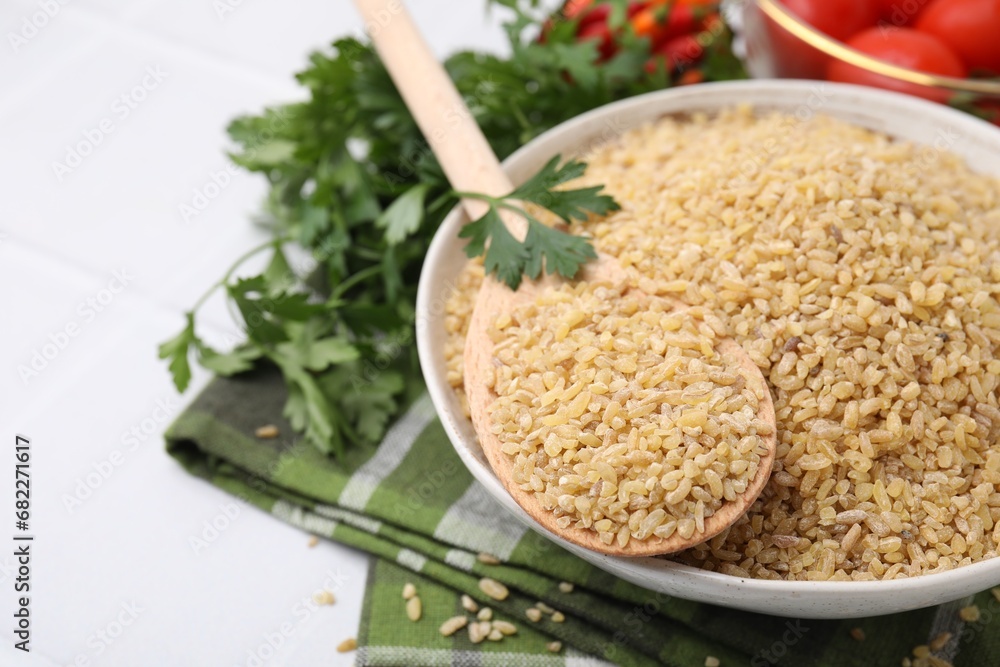 Bowl and spoon with raw bulgur on table, closeup Bowl and spoon with raw bulgur on table, closeup