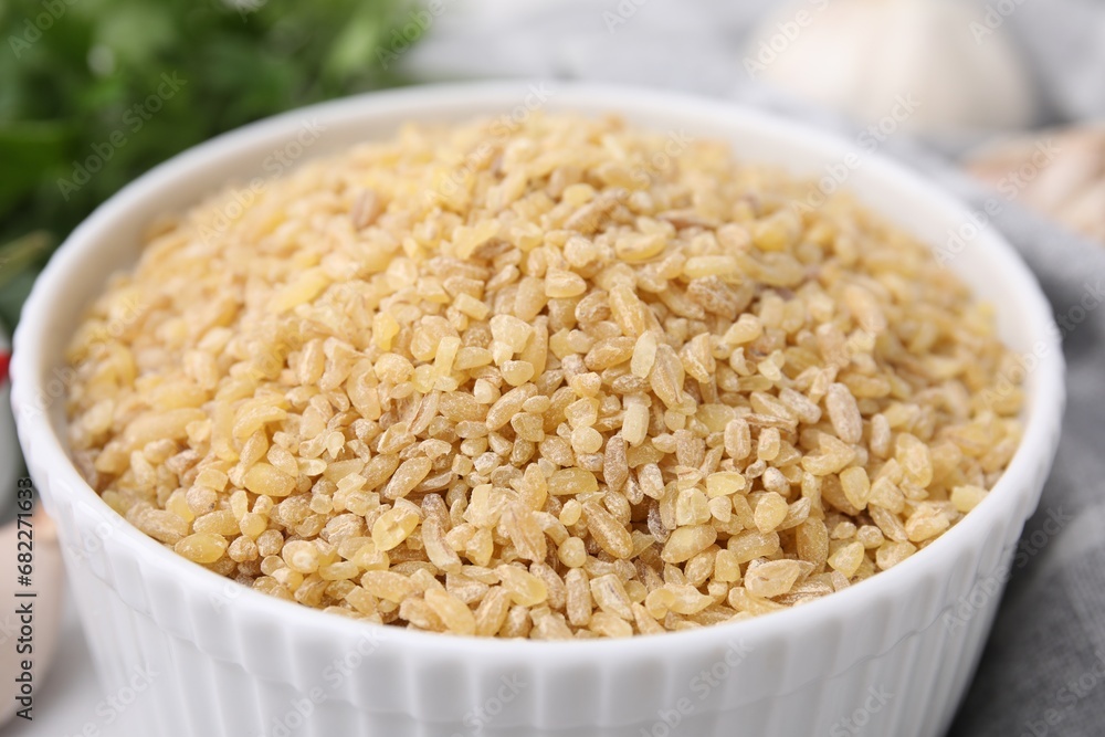 Raw bulgur in bowl on table, closeup Raw bulgur in bowl on table, closeup
