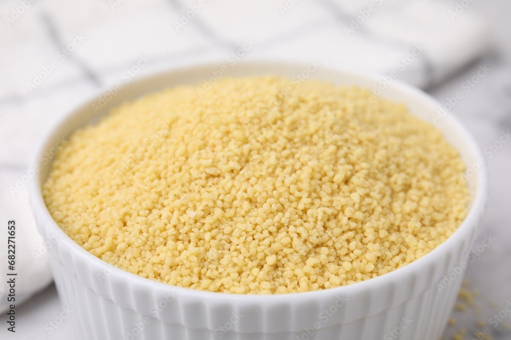 Raw couscous in bowl on light table, closeup Raw couscous in bowl on light table, closeup