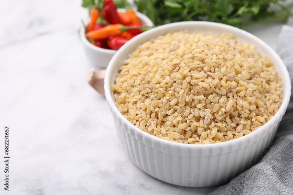 Raw bulgur in bowl on table, closeup Raw bulgur in bowl on table, closeup