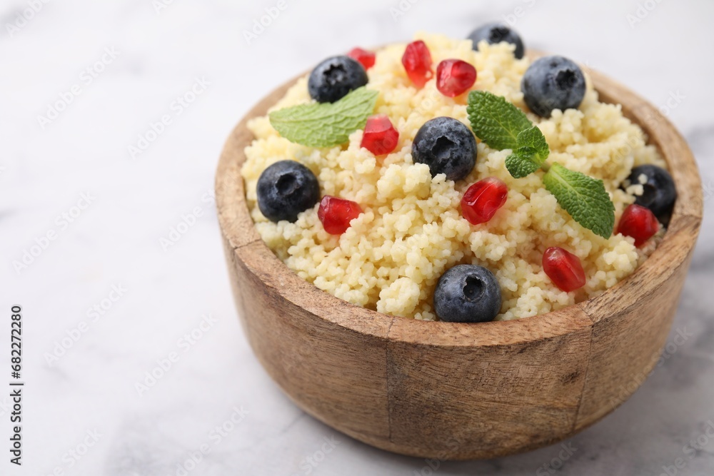 Bowl of tasty couscous with blueberries, pomegranate and mint on white marble table, closeup. Space for text Bowl of tasty couscous with blueberries, pomegranate and mint on white marble table, closeup. Space for text