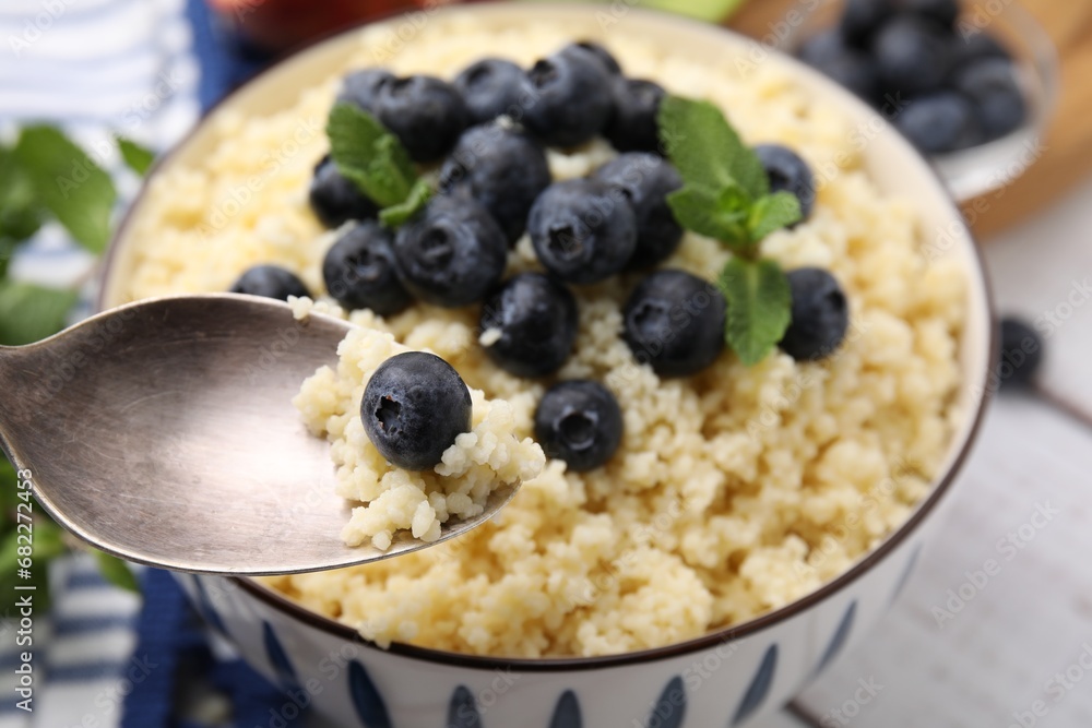 Eating tasty couscous with blueberries and mint from bowl, closeup Eating tasty couscous with blueberries and mint from bowl, closeup