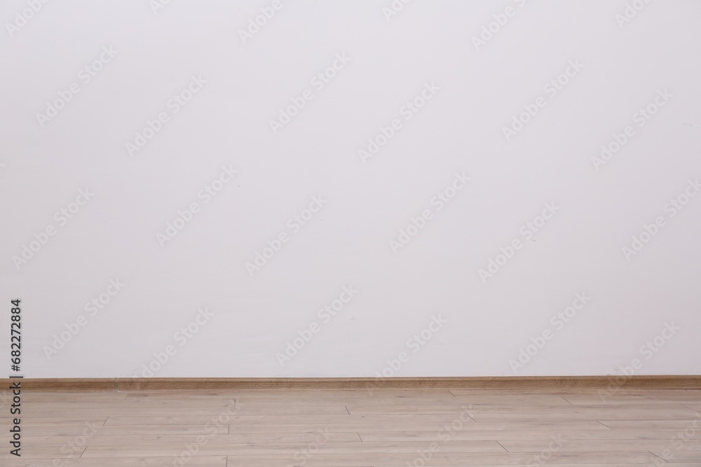 Empty white wall and wooden floor indoors, space for text Empty white wall and wooden floor indoors, space for text