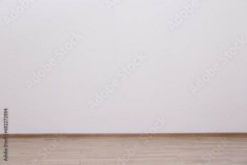 Empty white wall and wooden floor indoors, space for text
