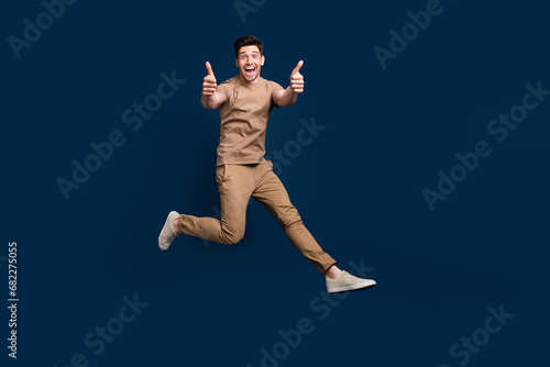 Full size photo of optimistic man dressed beige t-shirt running showing thumbs up good work isolated on dark blue color background