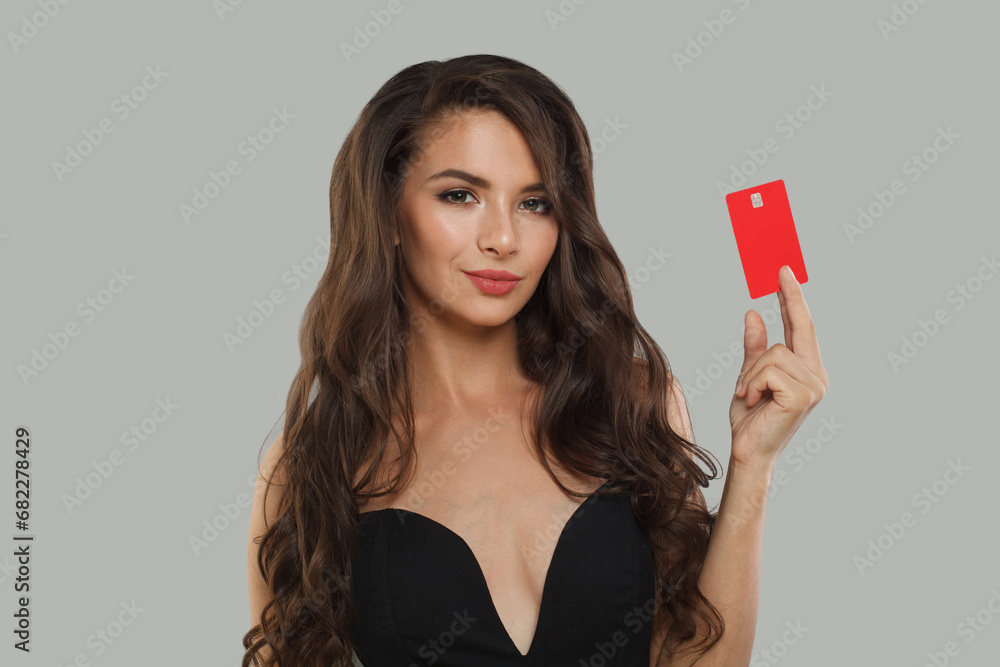 Cheerful model brunette lady holding debit card looking at camera isolated on grey studio wall banner background Cheerful model brunette lady holding debit card looking at camera isolated on grey studio wall banner background