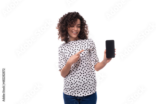 positive young brunette dressed in a blouse shows the screen of a mobile phone